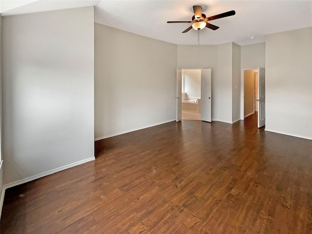 spare room featuring dark wood-style floors, baseboards, and ceiling fan