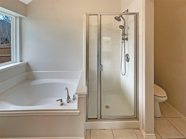 bathroom featuring a healthy amount of sunlight, tile patterned flooring, a shower stall, a garden tub, and toilet