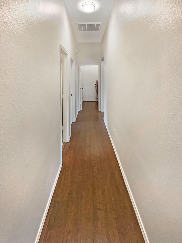 corridor with visible vents, baseboards, and wood finished floors