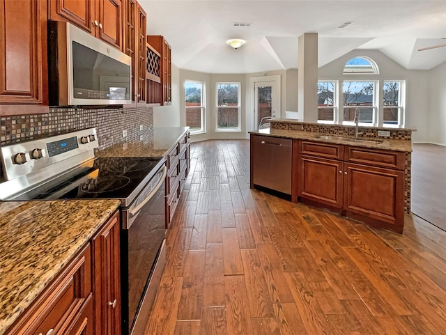 kitchen featuring visible vents, dark wood-type flooring, a sink, backsplash, and stainless steel appliances