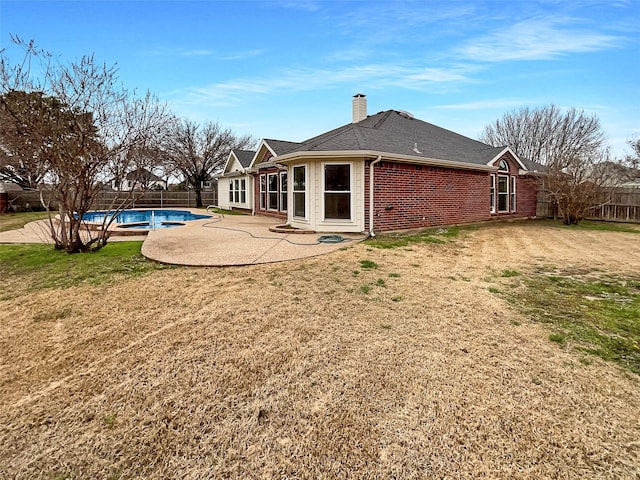 back of house featuring brick siding, a fenced backyard, a chimney, and a patio