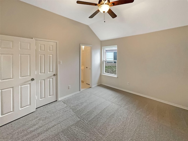 unfurnished bedroom with ceiling fan, baseboards, carpet, lofted ceiling, and ensuite bath