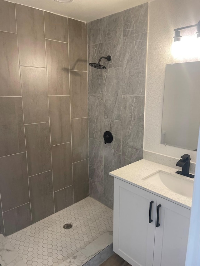 bathroom featuring a tile shower and vanity