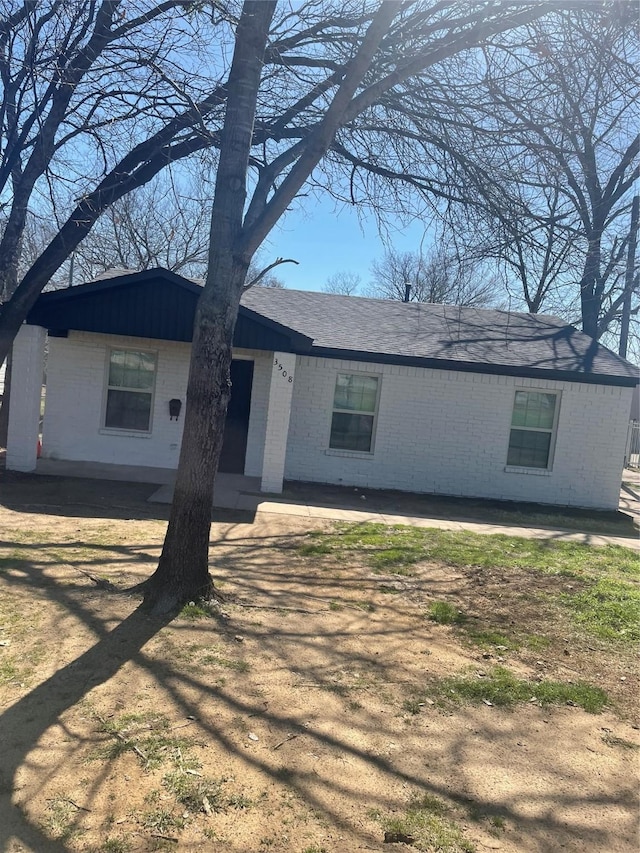 single story home featuring brick siding and roof with shingles