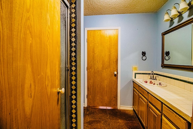 bathroom with a textured ceiling, vanity, and baseboards