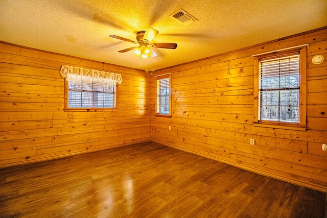 unfurnished room featuring visible vents, a healthy amount of sunlight, and wood finished floors