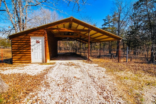 exterior space with a carport, gravel driveway, and fence