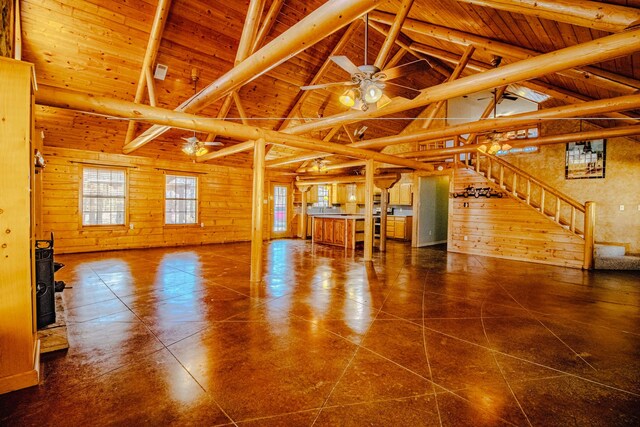 unfurnished living room with stairway, wood walls, and ceiling fan