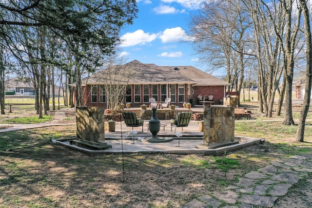 rear view of property with a sunroom, a patio, and brick siding