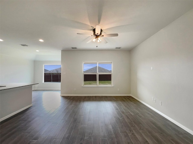 empty room featuring dark wood finished floors, visible vents, a ceiling fan, and baseboards