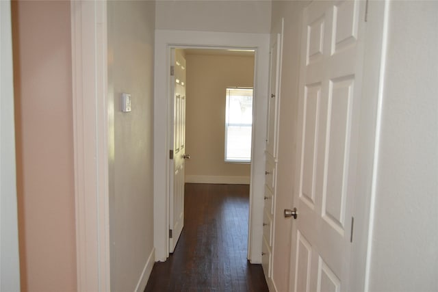 hall with dark wood-type flooring and baseboards