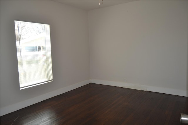 spare room with baseboards and dark wood finished floors