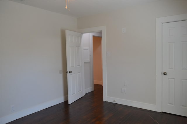 unfurnished bedroom with dark wood-style floors and baseboards