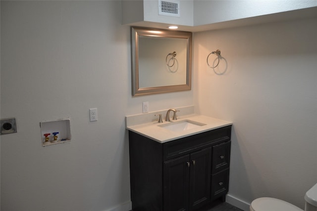 bathroom featuring visible vents, toilet, vanity, and baseboards