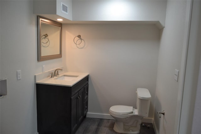 bathroom with visible vents, baseboards, toilet, wood finished floors, and vanity