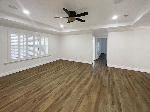 spare room featuring a tray ceiling, baseboards, and dark wood-type flooring