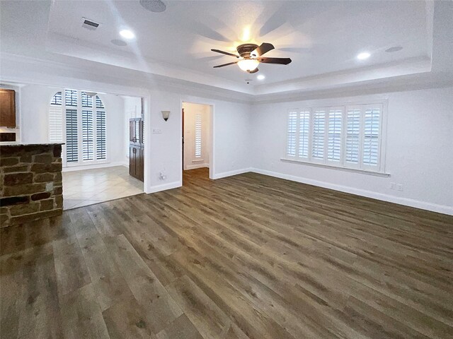 unfurnished living room with a raised ceiling, wood finished floors, visible vents, and baseboards