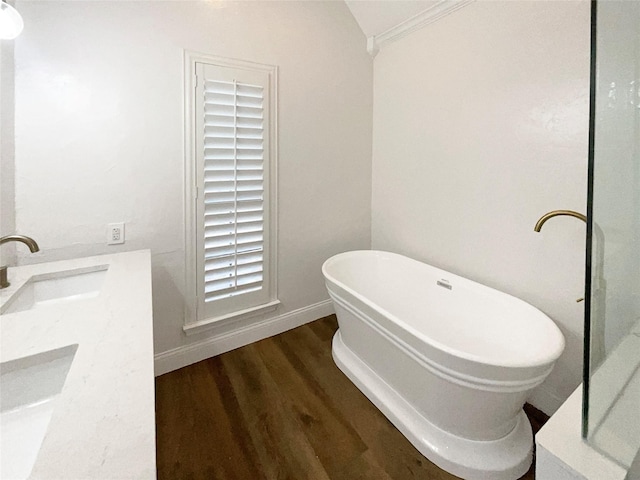 full bathroom featuring baseboards, wood finished floors, lofted ceiling, a freestanding tub, and a sink