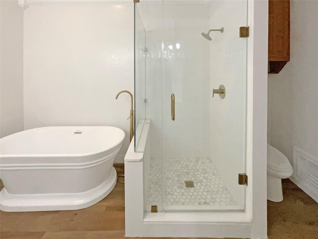 bathroom with a freestanding bath, a stall shower, and toilet