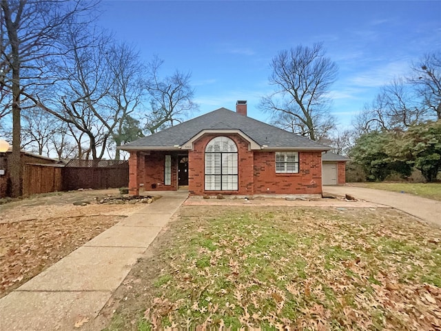 view of front facade featuring fence, driveway, a shingled roof, a chimney, and brick siding