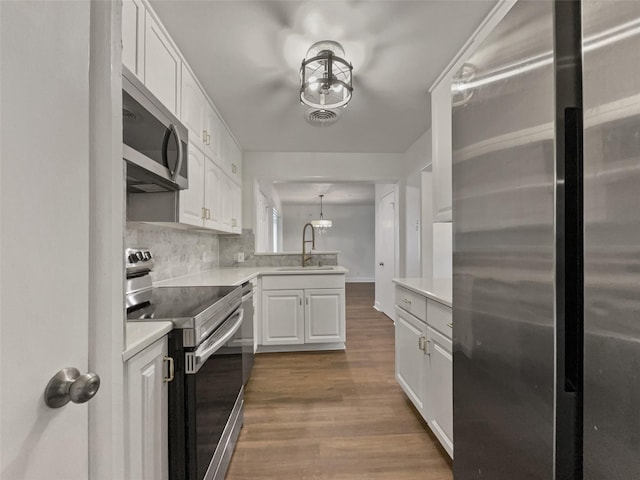 kitchen with visible vents, light countertops, appliances with stainless steel finishes, wood finished floors, and a sink