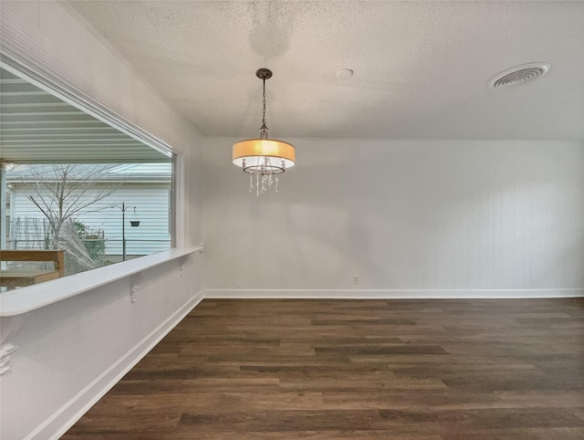 unfurnished dining area with dark wood-type flooring, baseboards, visible vents, and a textured ceiling