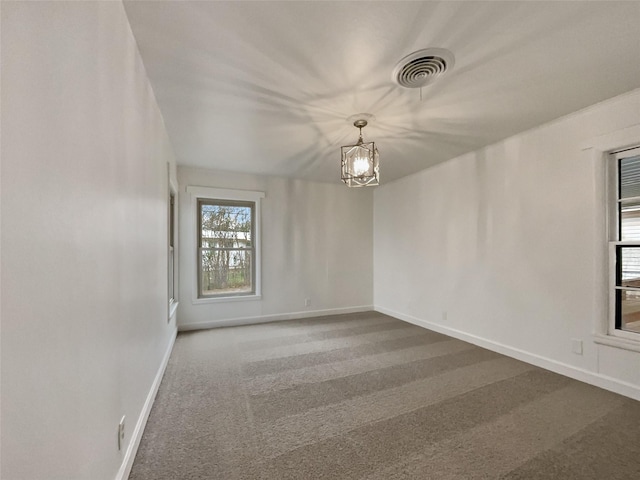 unfurnished room featuring a notable chandelier, baseboards, visible vents, and carpet floors