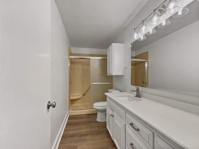 bathroom featuring vanity, wood finished floors, baseboards, a shower stall, and toilet