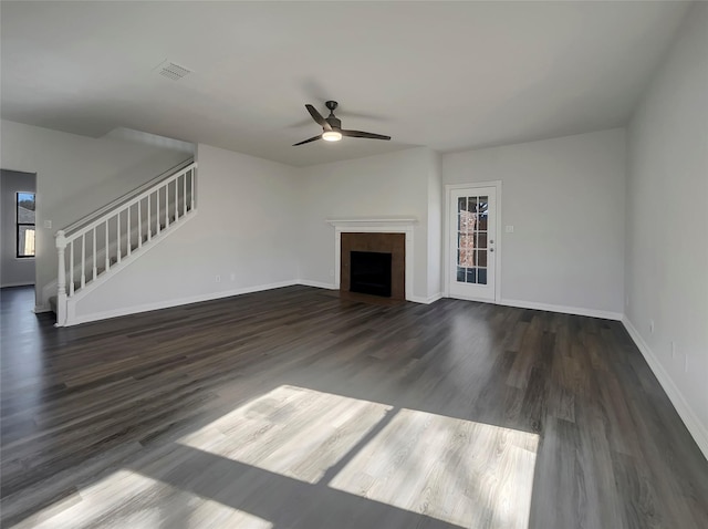 unfurnished living room with visible vents, baseboards, stairway, a fireplace, and wood finished floors