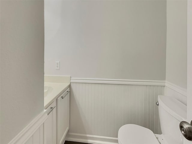 bathroom with vanity, toilet, and wainscoting