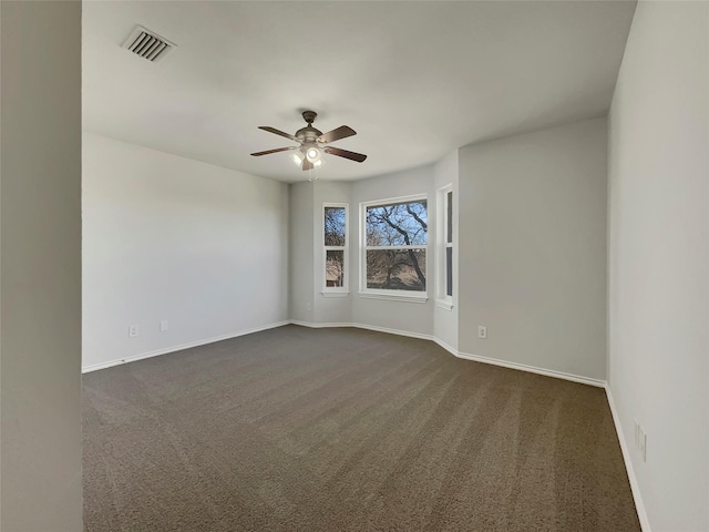 empty room with dark colored carpet, visible vents, baseboards, and a ceiling fan