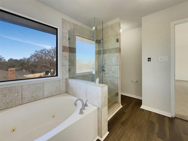 full bath featuring a shower stall, wood finished floors, a tub with jets, and baseboards