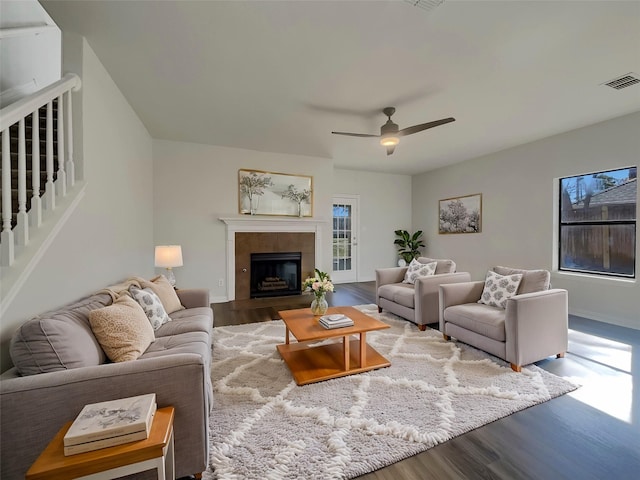 living area with visible vents, baseboards, ceiling fan, a fireplace, and wood finished floors