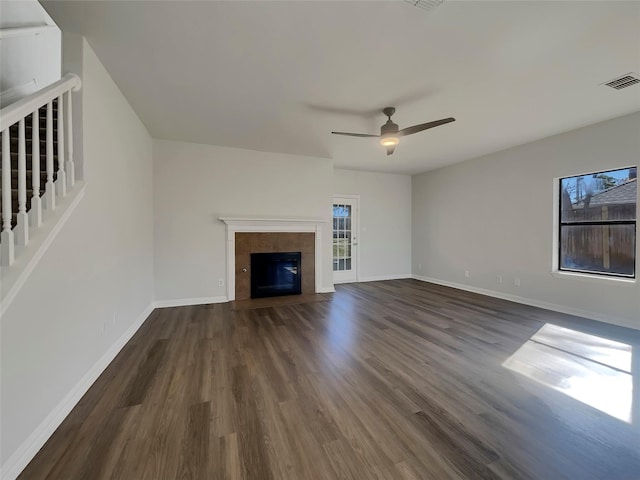 unfurnished living room featuring dark wood-style floors, visible vents, a tile fireplace, and baseboards