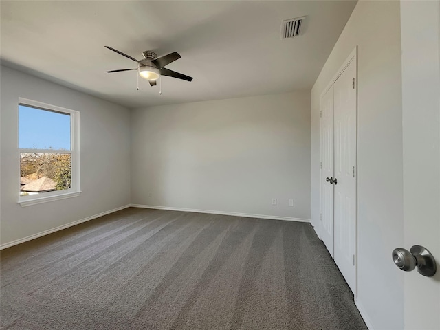 unfurnished bedroom featuring visible vents, baseboards, ceiling fan, and dark carpet