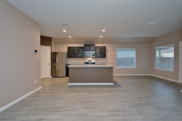 kitchen featuring light wood finished floors, visible vents, an island with sink, recessed lighting, and stainless steel appliances