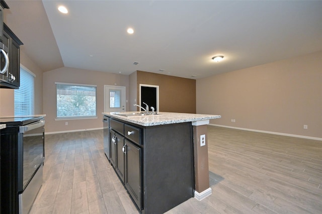 kitchen with light wood finished floors, a kitchen island with sink, appliances with stainless steel finishes, and a sink