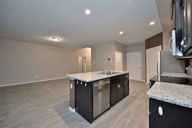 kitchen featuring light wood finished floors, baseboards, a center island with sink, appliances with stainless steel finishes, and a sink