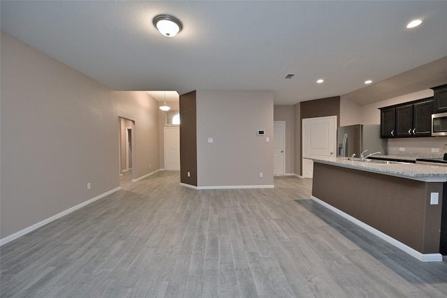 kitchen featuring open floor plan, appliances with stainless steel finishes, baseboards, and light wood-style floors