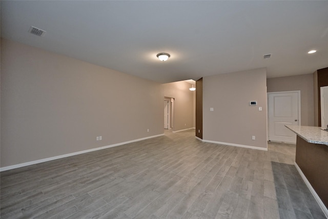 unfurnished living room featuring visible vents, light wood-type flooring, and baseboards