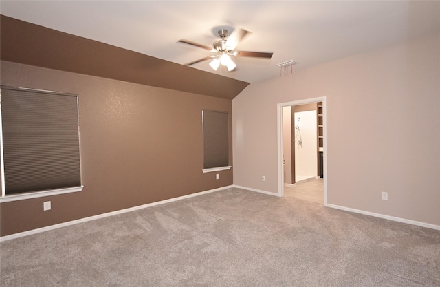 carpeted empty room with lofted ceiling, visible vents, baseboards, and ceiling fan