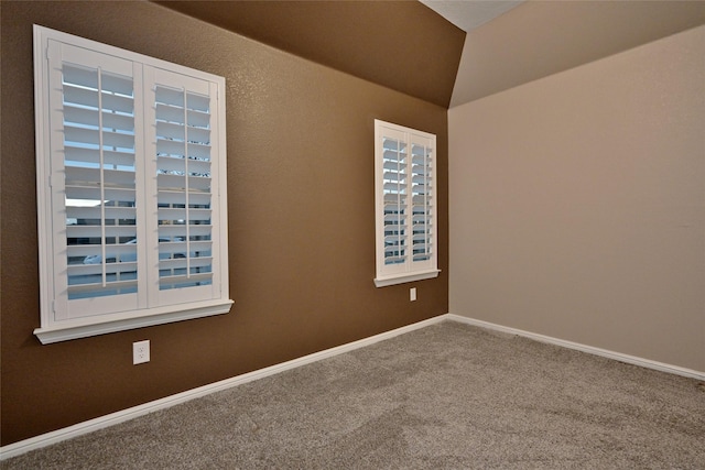 carpeted spare room featuring vaulted ceiling and baseboards