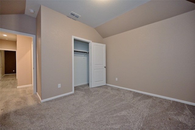 unfurnished bedroom with vaulted ceiling, light colored carpet, visible vents, and baseboards