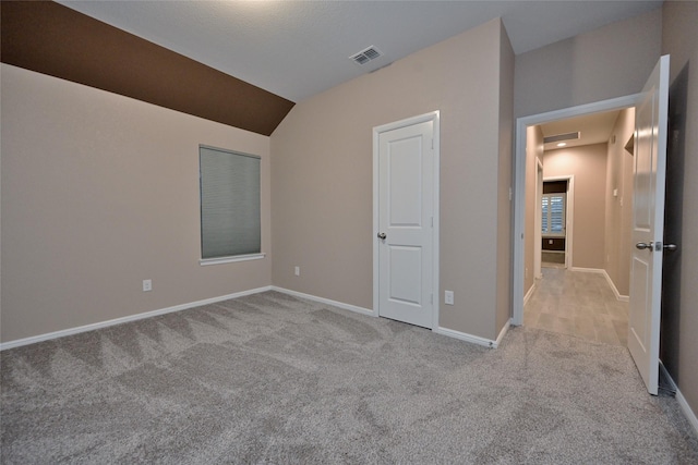 unfurnished bedroom with visible vents, carpet flooring, lofted ceiling, and baseboards