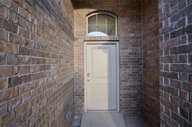 view of exterior entry featuring brick siding