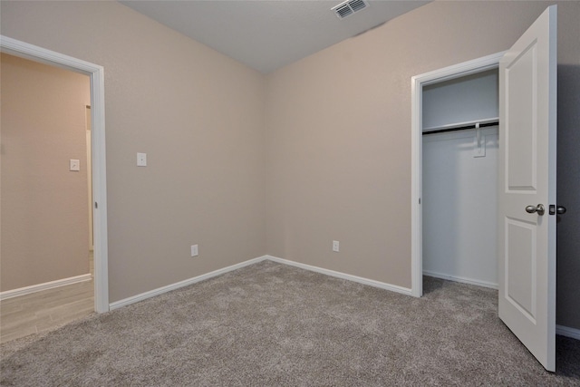 unfurnished bedroom with a closet, carpet flooring, baseboards, and visible vents