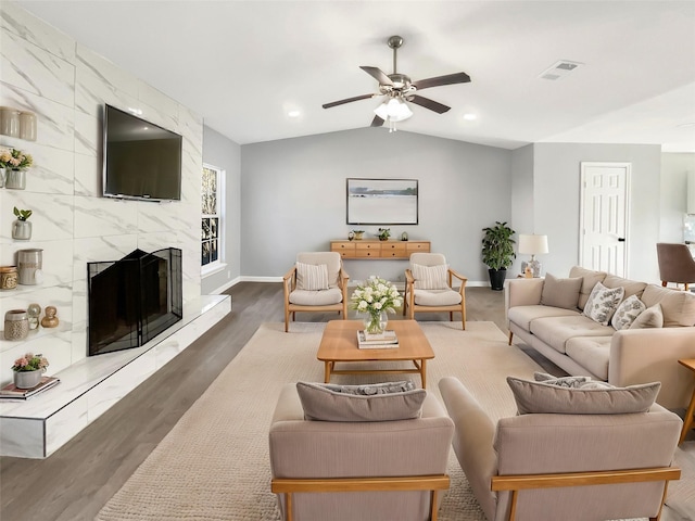 living room featuring a high end fireplace, visible vents, lofted ceiling, and wood finished floors