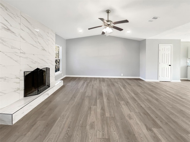 unfurnished living room featuring visible vents, lofted ceiling, wood finished floors, baseboards, and a tile fireplace