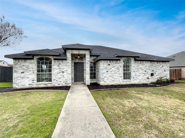 view of front of house with brick siding, a front lawn, and fence