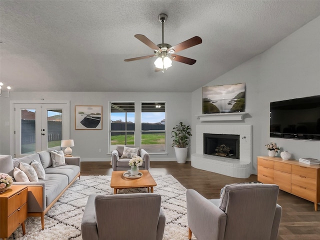 living room featuring a textured ceiling, dark wood-style floors, a fireplace, and vaulted ceiling